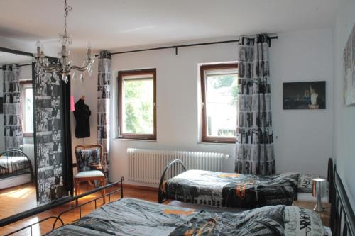 a bedroom with two beds and a chair at Pension Rodenburg in Duppach