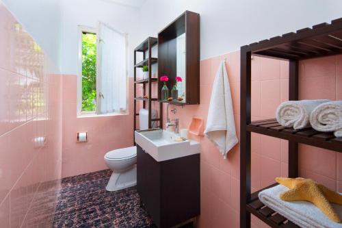 uma casa de banho rosa com um lavatório e um WC em Ana Apartment em Rabac