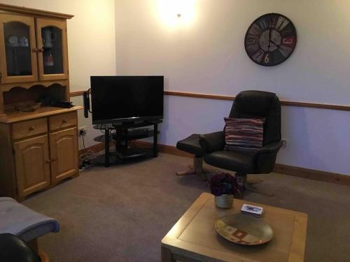 a living room with a tv and a chair and a clock at Musadale in Brae