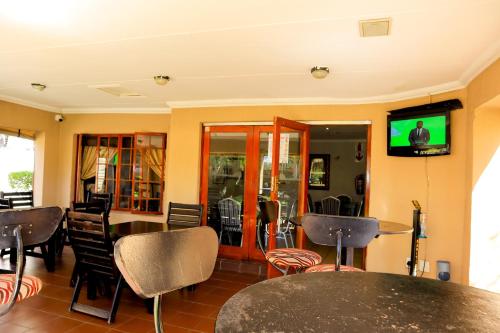a restaurant with tables and chairs and a tv on the wall at Masai Shuttles And Hotel in Polokwane