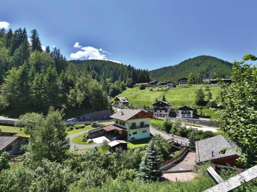 ein Dorf in den Bergen mit Häusern und Bäumen in der Unterkunft Rider Hotel Obereggen in Obereggen