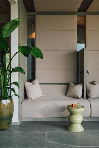 a white bed with pillows and a plant in a room at ALPIANA - green luxury Dolce Vita Hotel in Vollan