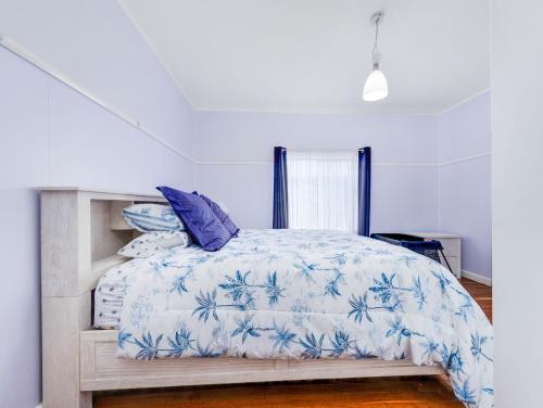 a bedroom with a bed with a blue and white comforter at Beachfront Escape Relaxing Getaway in Batehaven in Sunshine Bay