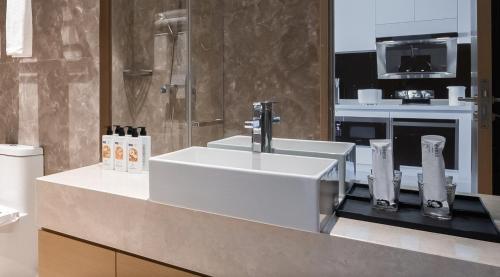 a bathroom with a white sink and a shower at 来咖民宿酒店三亚海棠湾亚特兰蒂斯棠岸店 in Fengtang
