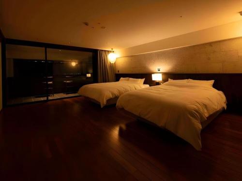 a hotel room with two beds and a window at Kannawa Onsen Hotel Sansuikan in Beppu