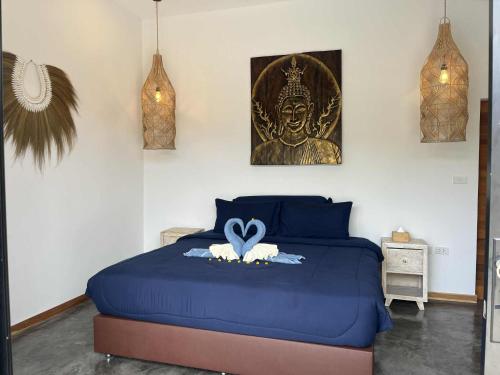 una camera da letto con un letto blu con una statua sopra di Villa ANSEJU Tranquillité, Jardin Tropical & 3 Chambres Spacieuses a Hua Thanon Beach