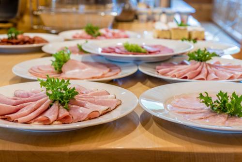 a table topped with plates of meats and vegetables at Penzion Viktória in Ždiar