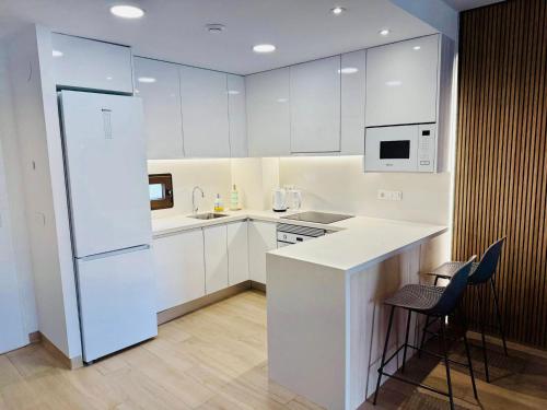 une cuisine avec des armoires blanches et un réfrigérateur blanc dans l'établissement Apartament z Basenem i Jacuzzi Benidorm Finestrat, à Finestrat