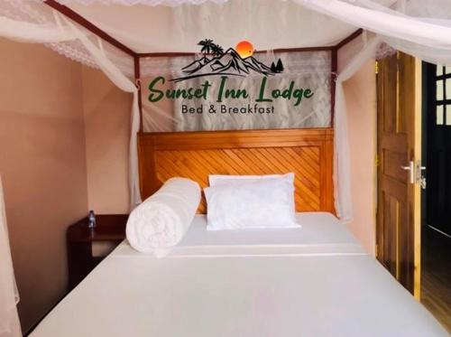 a bed in a small room with a sign on it at Sunset Inn Lodge in Arusha