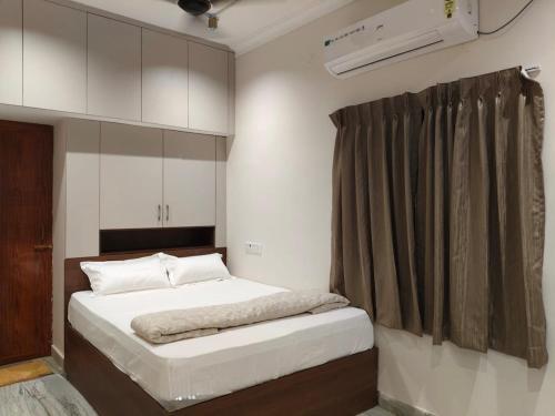 a bedroom with a bed with white sheets and a window at Ravis ishwaryam villa in Tiruchchendūr