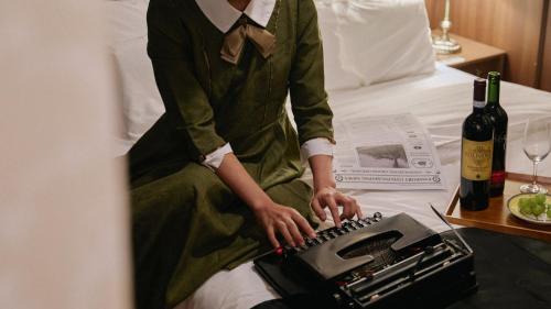 a person is sitting on a bed with a typewriter at Stay Passport Express Gyeongseong Cheongnyangni in Seoul