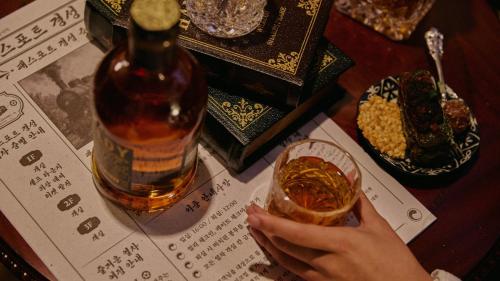 a person holding a drink and a bottle of whiskey at Stay Passport Express Gyeongseong Cheongnyangni in Seoul