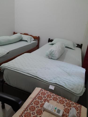 two beds in a room with a table at The Gambir Sawit Syariah Homestay in Ngabean