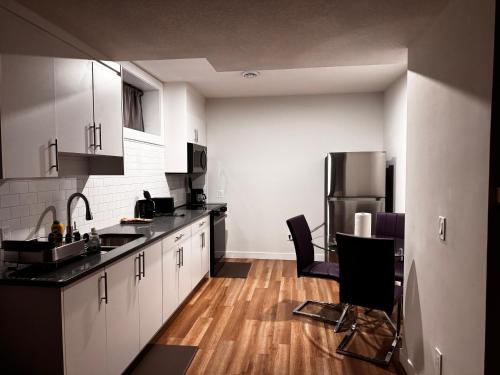 a kitchen with black counter tops and a refrigerator at Homey Basement Suite by Gaudi in Calgary