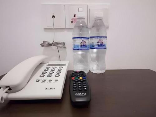 two bottles of water next to a phone and a remote control at D Nice Hotel in George Town