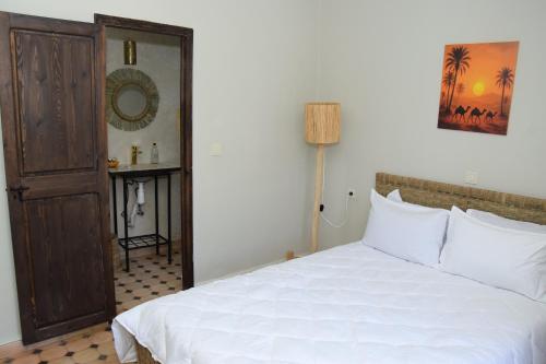 a bedroom with a white bed and a mirror at La PERLE DE OUIRGANE in Ouirgane