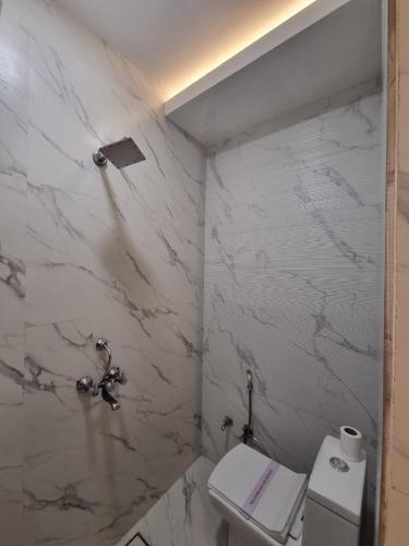 a bathroom with a toilet and a marble wall at Lucky Restaurant & Guest House in Agra