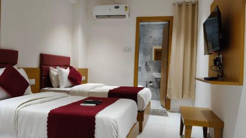 a hotel room with two beds and a television at Hotel Pine View in Rajkot