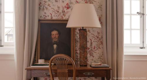 a portrait of a man on a desk with a lamp at Les Sources de Vougeot in Vougeot