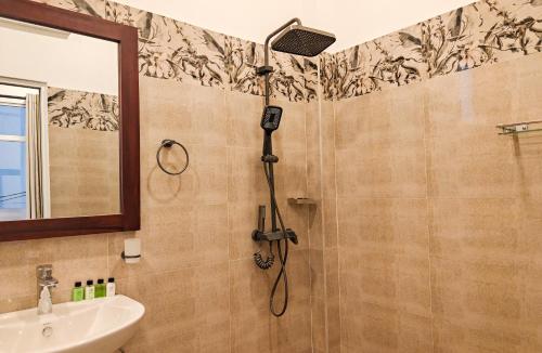 a shower in a bathroom with a sink and a mirror at Sasnidu Villa in Hikkaduwa