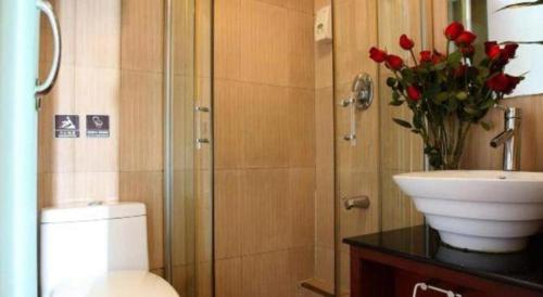 a bathroom with a toilet and a sink and red roses at Hangzhou Bokai Westlake Hotel in Hangzhou