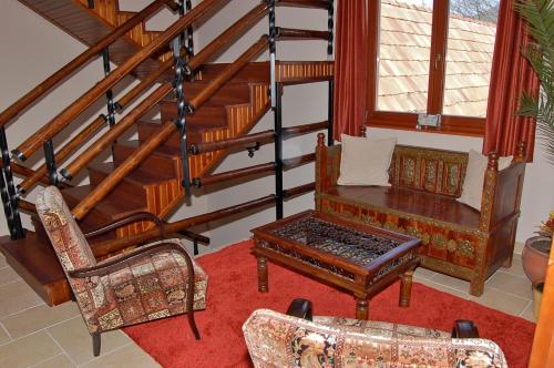 a living room with a table and chairs and stairs at Malomdűlő Farmház in Pilisborosjenő