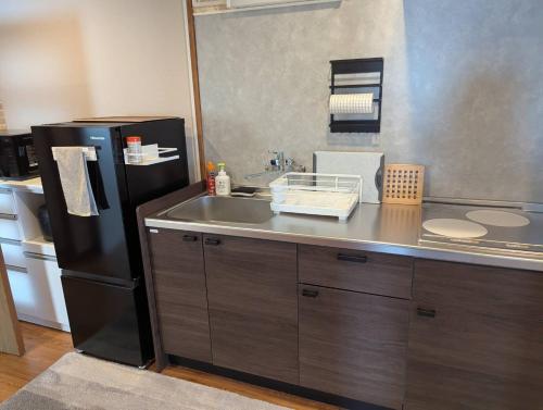 a kitchen with a black refrigerator and a sink at Uemura Building 202 - Vacation STAY 19716 in Kirishima