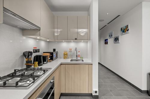 a kitchen with white cabinets and a stove top oven at Bright, Breezy and Central 1BR with Extra Room in Dubai