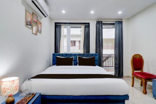 a bedroom with a blue bed and a red chair at Super Townhouse Rispana River Dehradun Formerly Nivasa Home Stays in Dehradun