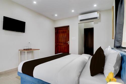 a bedroom with a bed and a tv on the wall at Super Townhouse Rispana River Dehradun Formerly Nivasa Home Stays in Dehradun