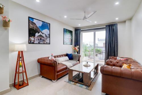 a living room with two leather couches and a table at Super Townhouse Rispana River Dehradun Formerly Nivasa Home Stays in Dehradun