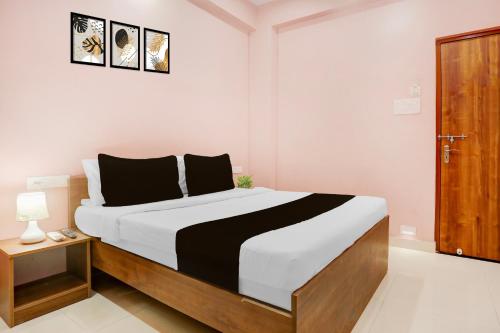 a bedroom with a large bed and a wooden door at Super Hotel O IIT Varanasi Formerly Shree Gopal Upwan in Varanasi