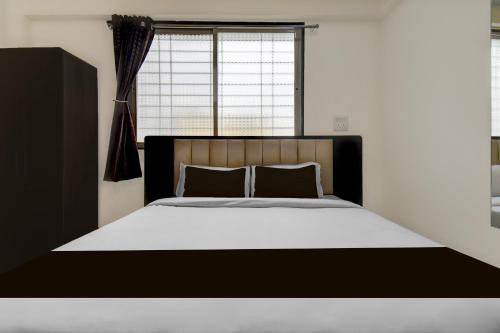 a bedroom with a black and white bed with a window at Super Townhouse Pimple Nilakh Pune in Dāpuri