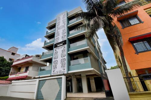 a building with a palm tree in front of it at Super Townhouse Pimple Nilakh Pune in Dāpuri