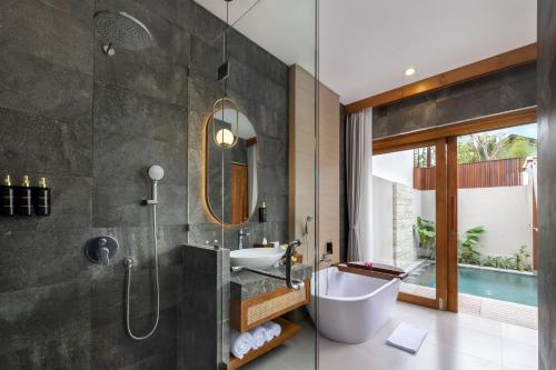 a bathroom with a tub and a sink and a shower at La Tropica Canggu Bali By Kanaya Hospitality in Canggu