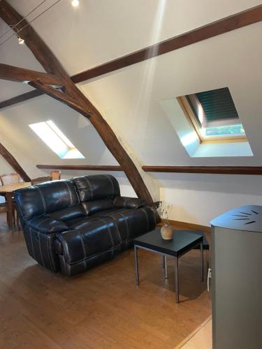 a living room with a leather couch and a table at Gîte tourangeau dans la vallée de la Loire in Bléré