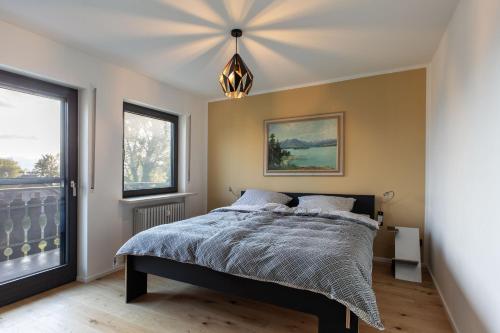 Un dormitorio con una cama y una ventana grande. en Designer-Oberstüberl mit Seeblick auf den Chiemsee & Alpenpanorama, en Seebruck
