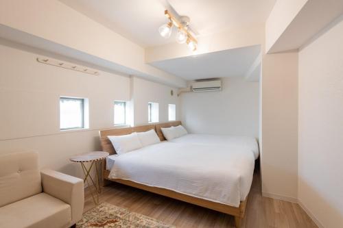 a white bedroom with a bed and a chair at 東新宿1007 Good location within 15 minutes of Shinjuku Station in Tokyo