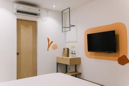 a bedroom with a bed and a tv on a wall at Sanctuary Hotel Slipi in Jakarta