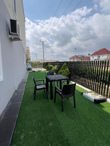 a patio with a table and chairs on the grass at Luxury Smart 3-Bedroom Semi-Detached Apartment in Abuja