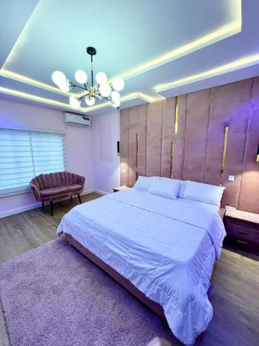 a bedroom with a large white bed and a couch at Luxury Smart 3-Bedroom Semi-Detached Apartment in Abuja
