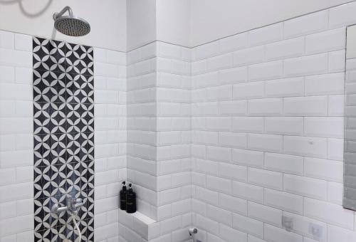 - une douche carrelée de blanc avec du carrelage noir et blanc dans l'établissement Damar Kusumo Exclusive Guest House, à Seturan