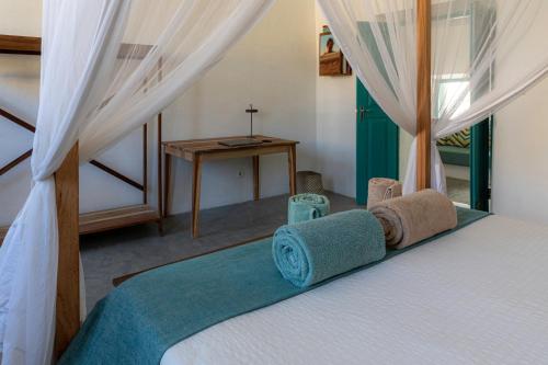 1 dormitorio con 1 cama con cortinas y mesa en Casa da Lua, en Isla de Mozambique