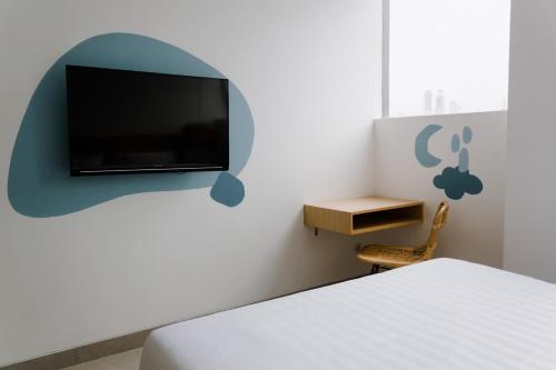a bedroom with a bed and a tv on a wall at Sanctuary Hotel Slipi in Jakarta