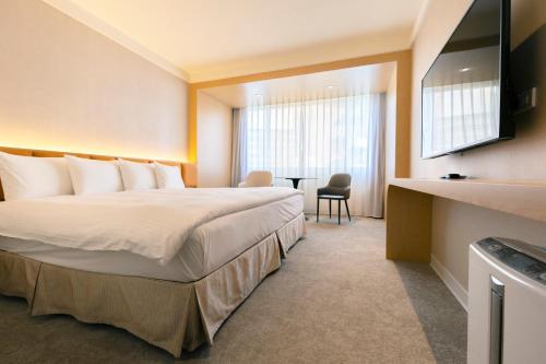 a hotel room with a large bed and a table at Hotel Tainan in Tainan
