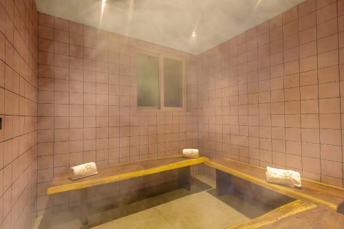 a tiled bathroom with two benches and a window at SaffronStays Grand Odyssy in Jambrung 