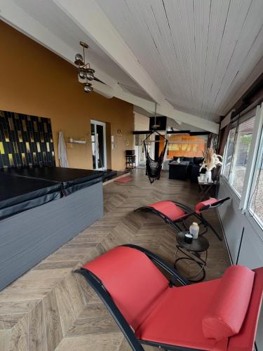 a living room with red chairs and a bar at L’Instant in Caupenne