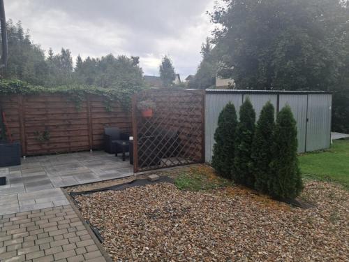 a backyard with a fence and two trees and a chair at Apartamenty Na Kowańcu in Nowy Targ