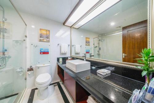 a bathroom with a sink and a toilet and a mirror at Liyuan Hotel in Shenzhen