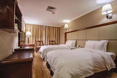 a hotel room with two beds with white sheets at Liyuan Hotel in Shenzhen